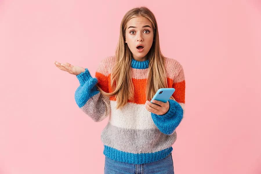 青い携帯電話を手に持ち、何か質問でもしているかのような表情の若い女性。