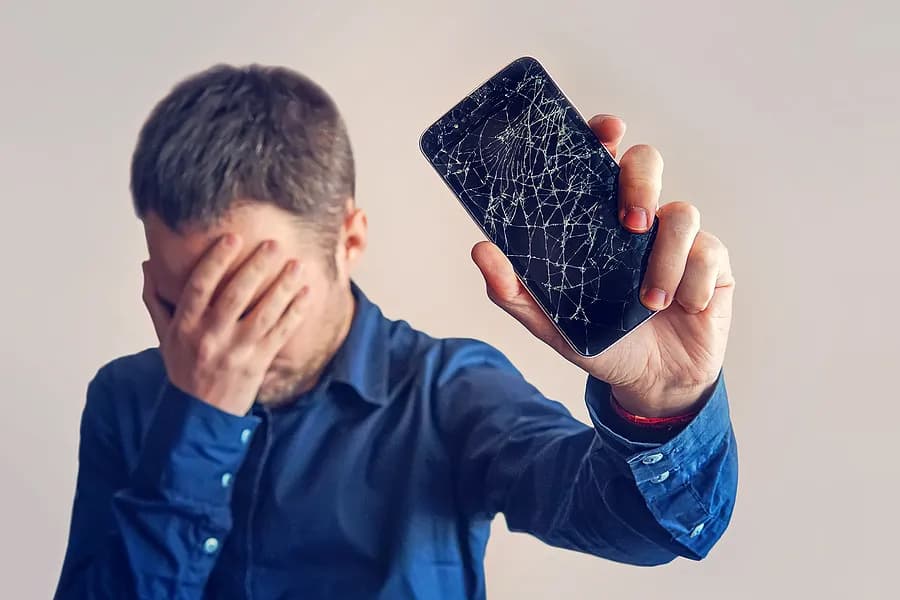 目を覆い、携帯電話を自分から離して持っている男性。