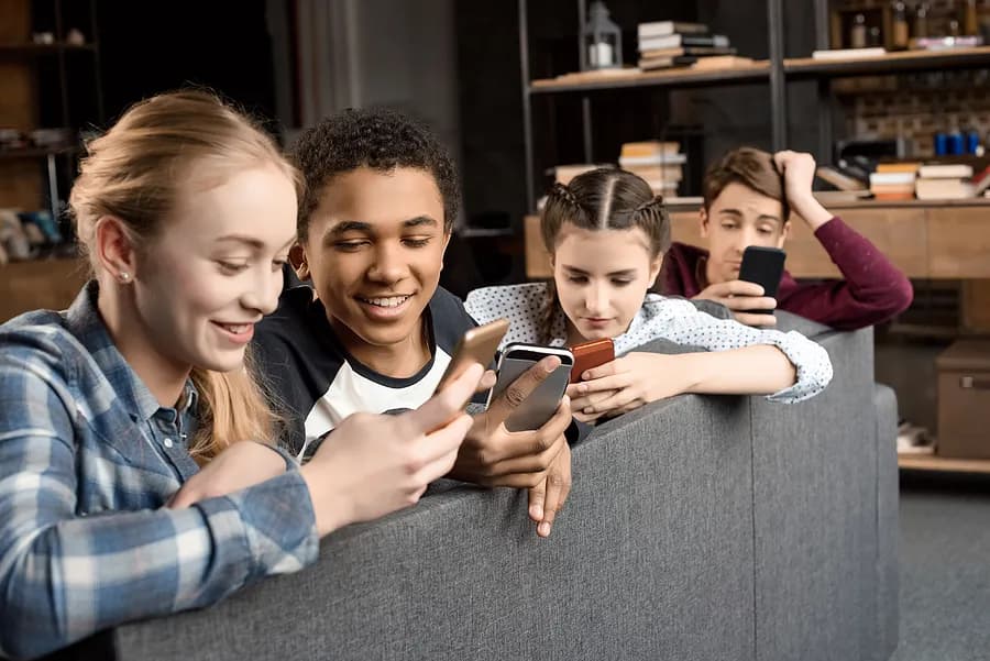 携帯電話を見ている4人の10代の若者たち。