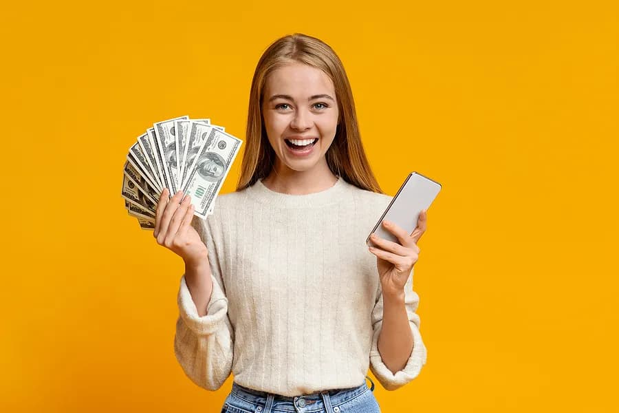 携帯電話とお金を手にした女性。