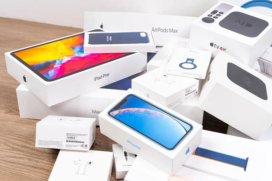 iPhone、iPad Pro、AirPods、Apple Watch、Apple TVなどのApple製品の箱が、木製の台の上に積み上げられている。