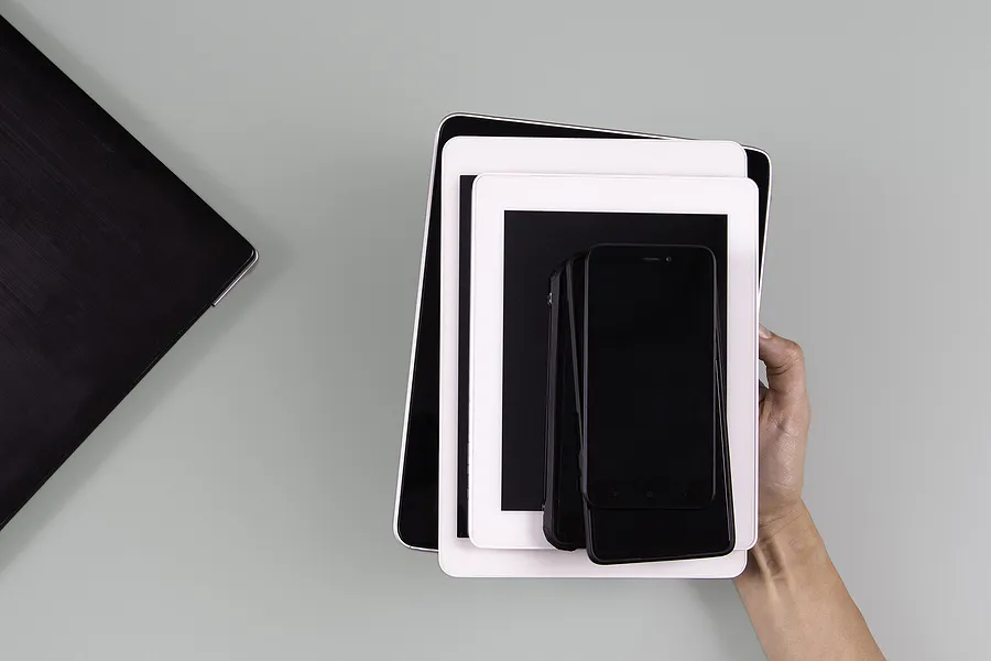 スマートフォンやタブレットなど、積み重ねられたモバイル端末を手に持つ姿。これは、再生品の携帯電話市場の拡大と今後のトレンドを象徴している。