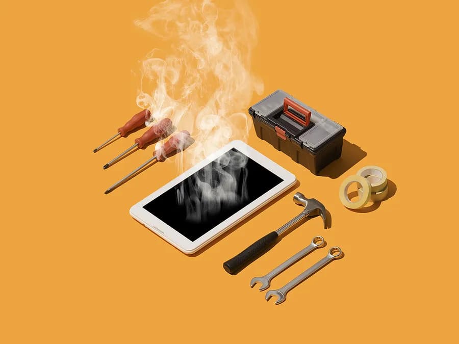 煙を吐き出しているスマートフォンが、ドライバー、レンチ、ハンマー、テープ、小さな工具箱などの修理道具に囲まれたオレンジ色の台の上に置かれており、スマートフォンの過熱と修理を象徴している。